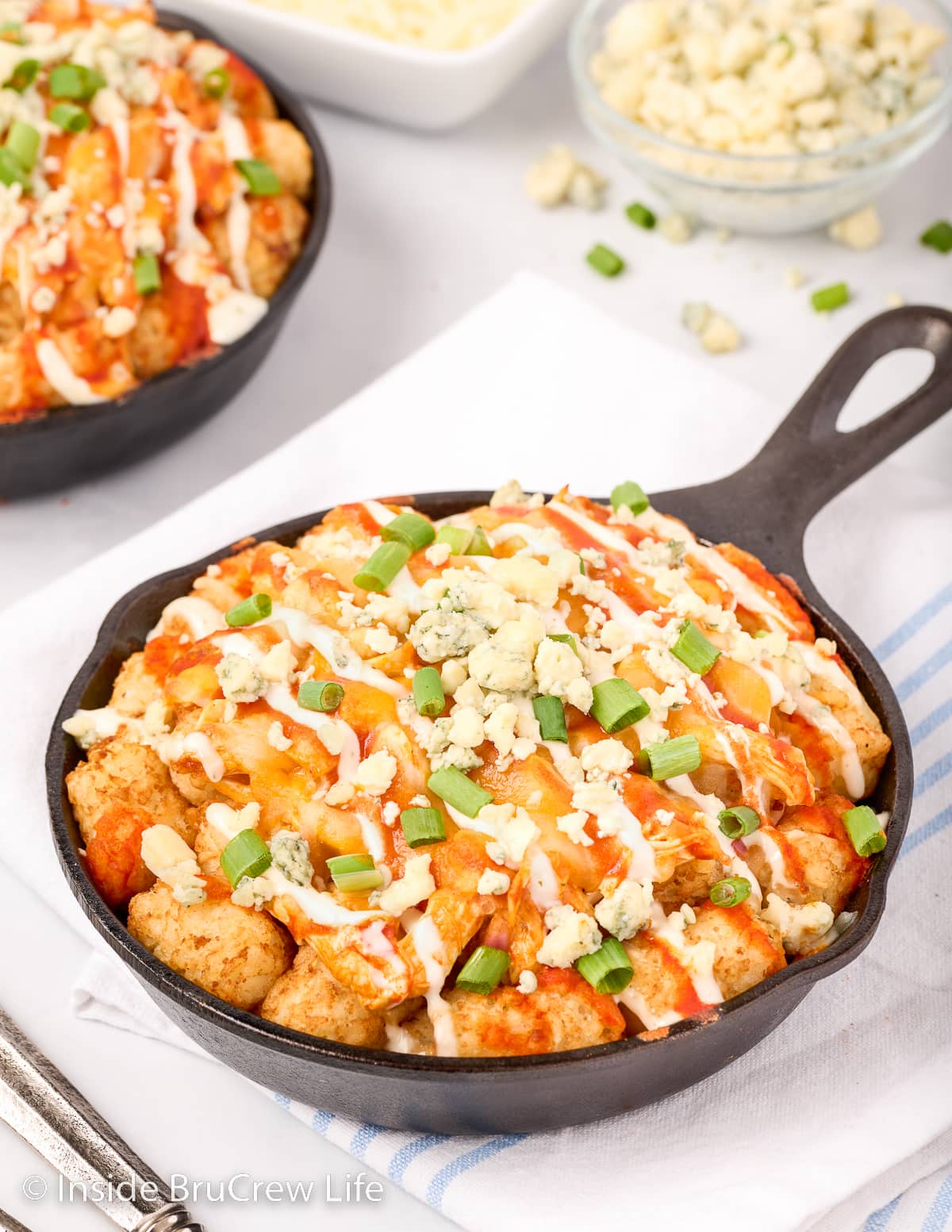 A black skillet filled with cheesy buffalo tots.