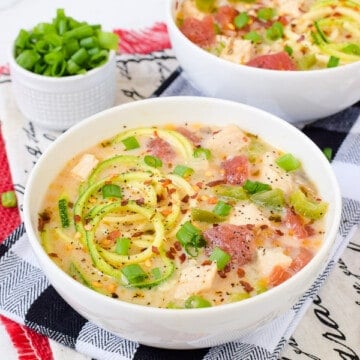 A white bowl filled with low carb chicken zoodle soup.