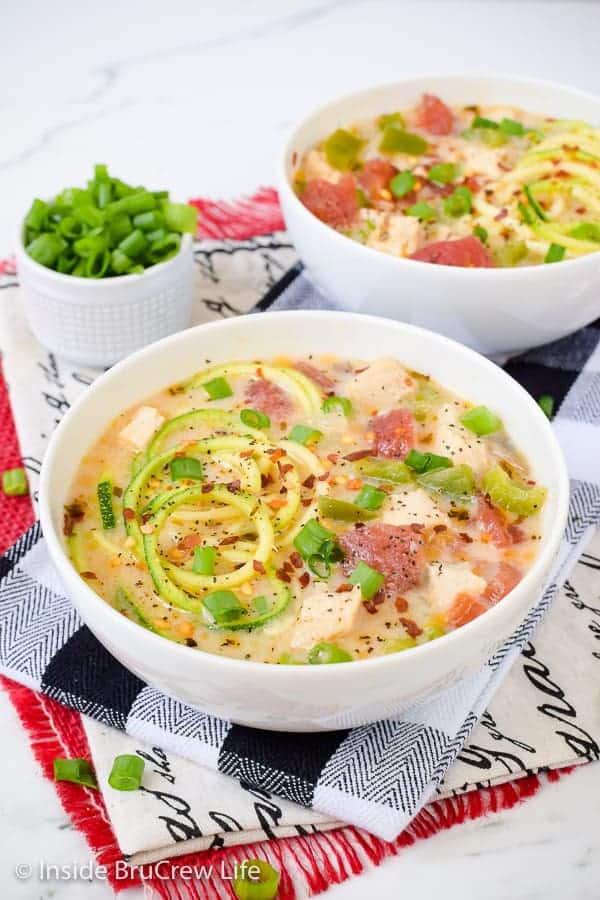 Two white bowls filled with chicken alfredo soup with zoodles.