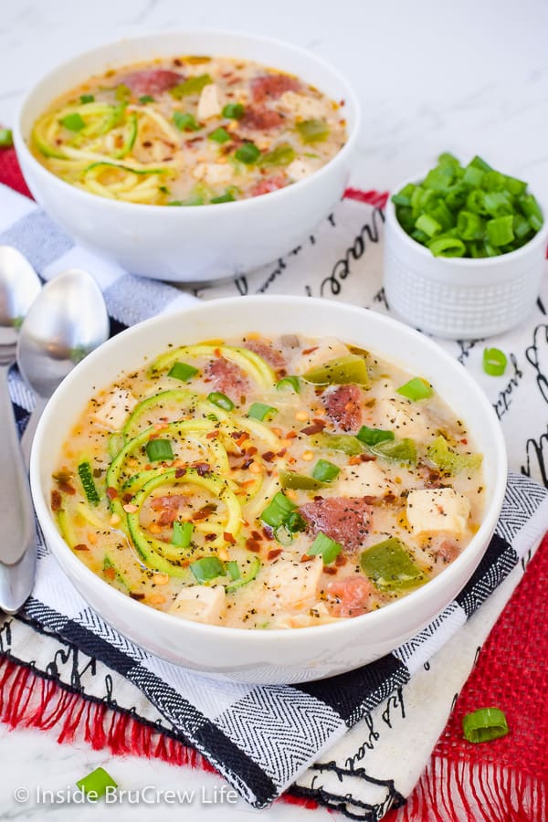 Two white bowls filled with a chicken alfredo zoodle soup.