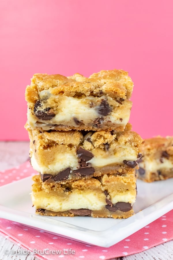 A stack of chocolate chip cheesecake bars on a white plate with more behind it.