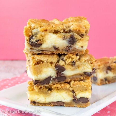 A white plate with a stack of chocolate chip cheesecake cookie bars on it.