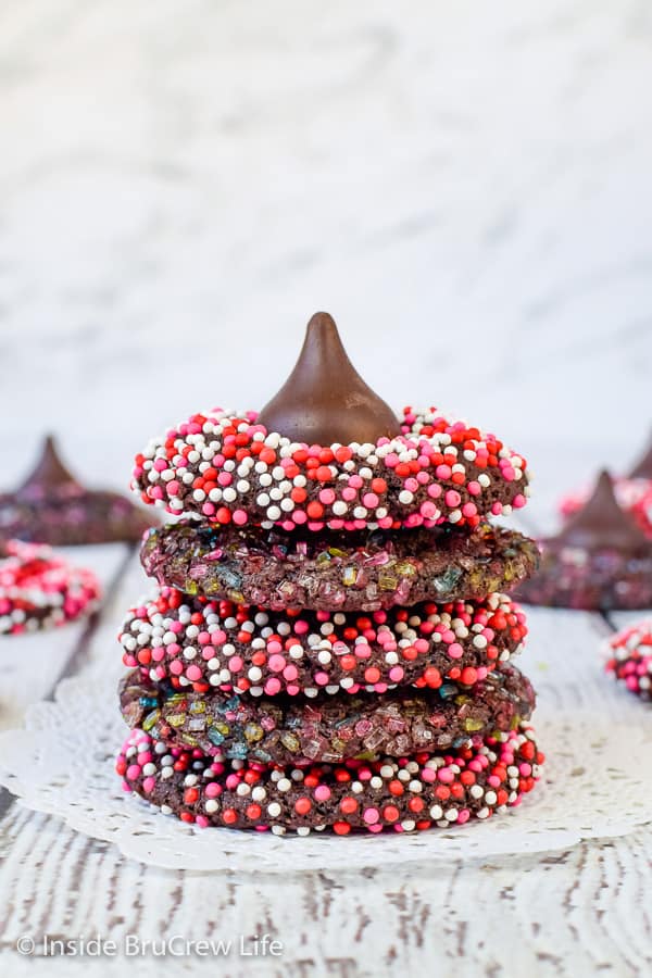A stack of 4 chocolate cookies covered in sprinkles topped with a Hershey kiss.
