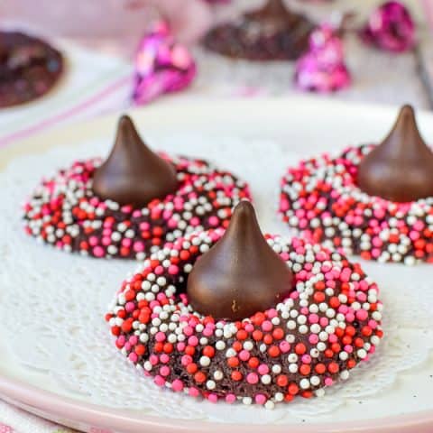 A plate full of chocolate cookies with sprinkles and a Hershey kiss on top.