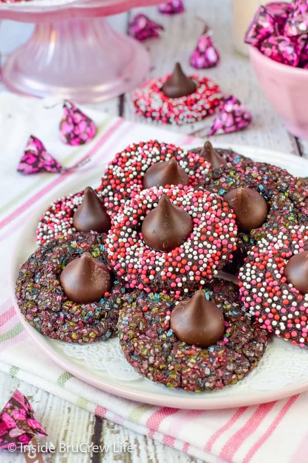 A plate full of chocolate cookies with sprinkles and a Hershey kiss on top.