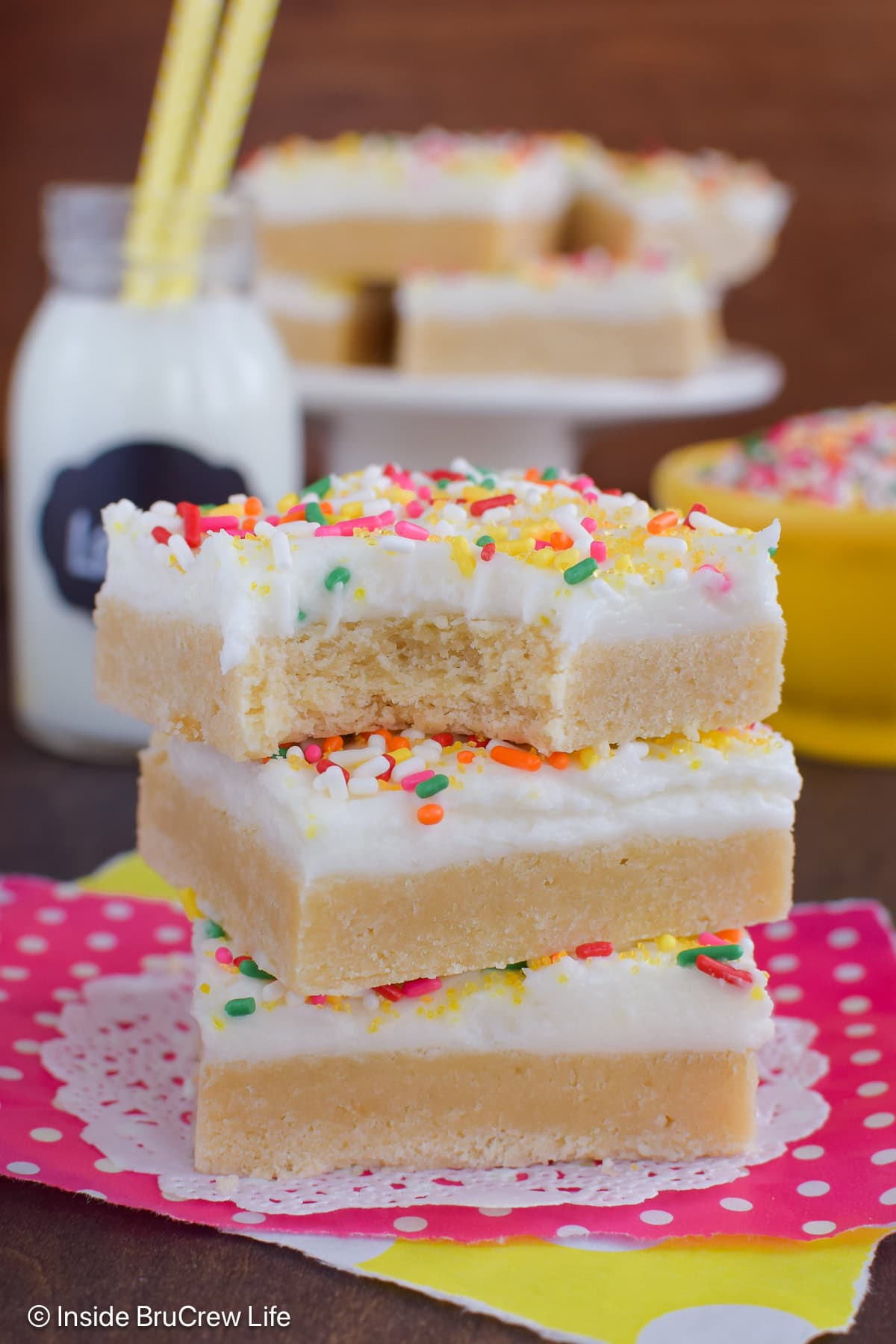 Three cookie bars stacked together and the top one has a bite out of it.