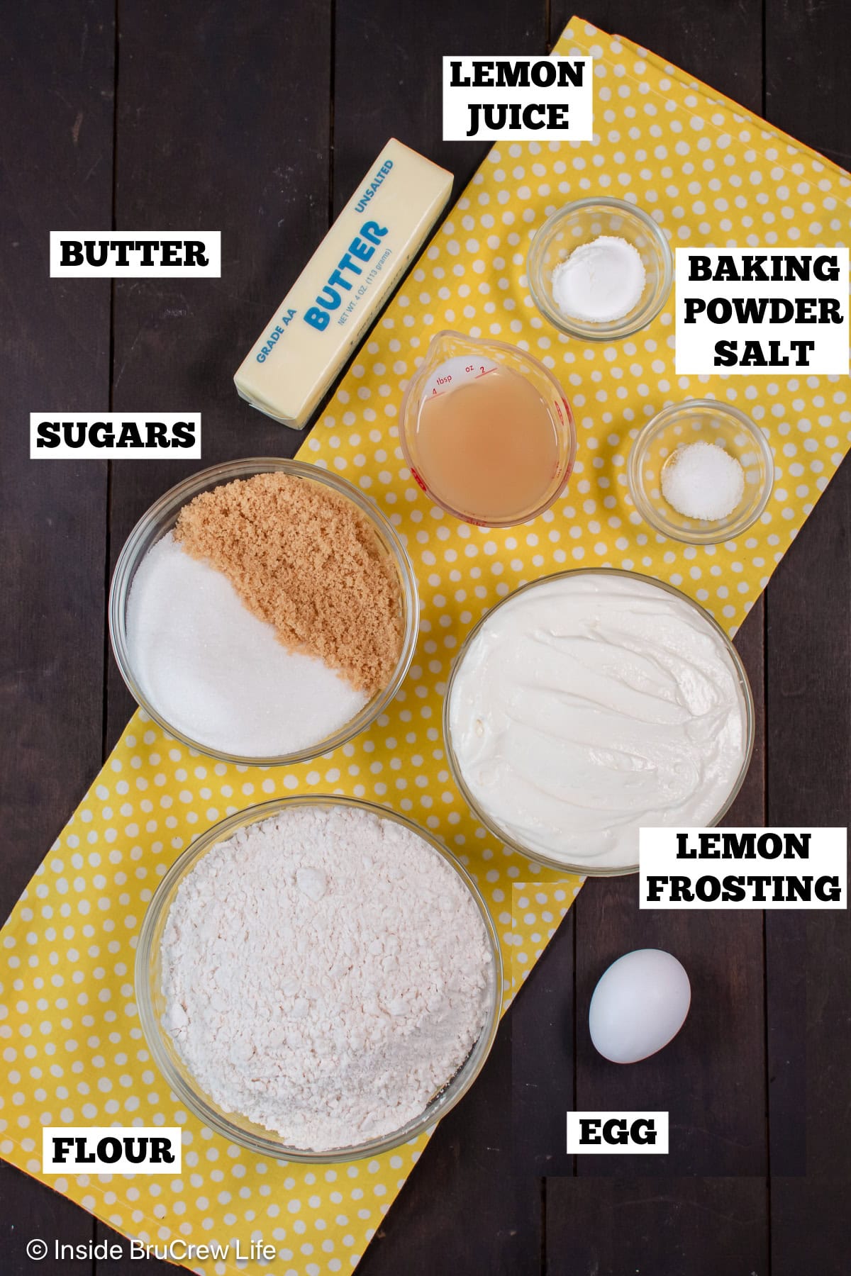 A brown board with bowls of ingredients needed to make lemon sugar cookie bars.