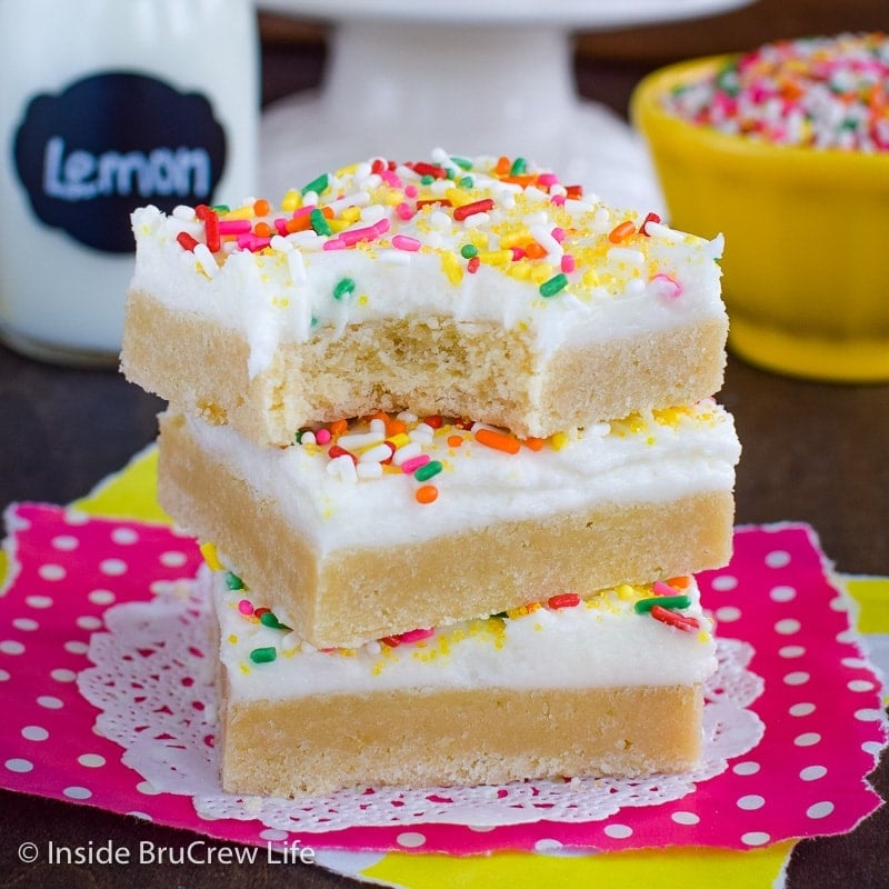 Three frosted lemon bars cookies stacked on top of each other.