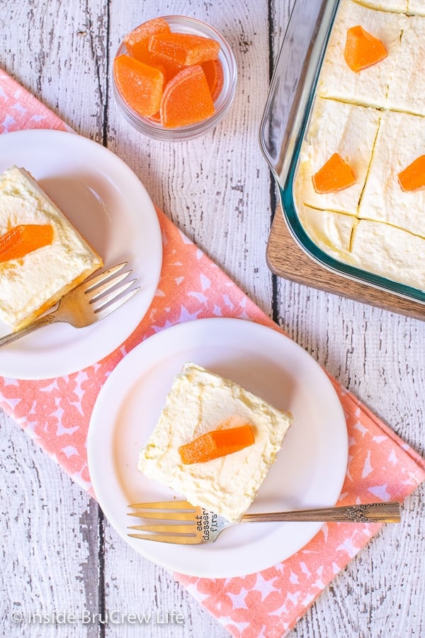 Overhead picture of white plates with orange creamsicle poke cake on them and a cake pan beside them