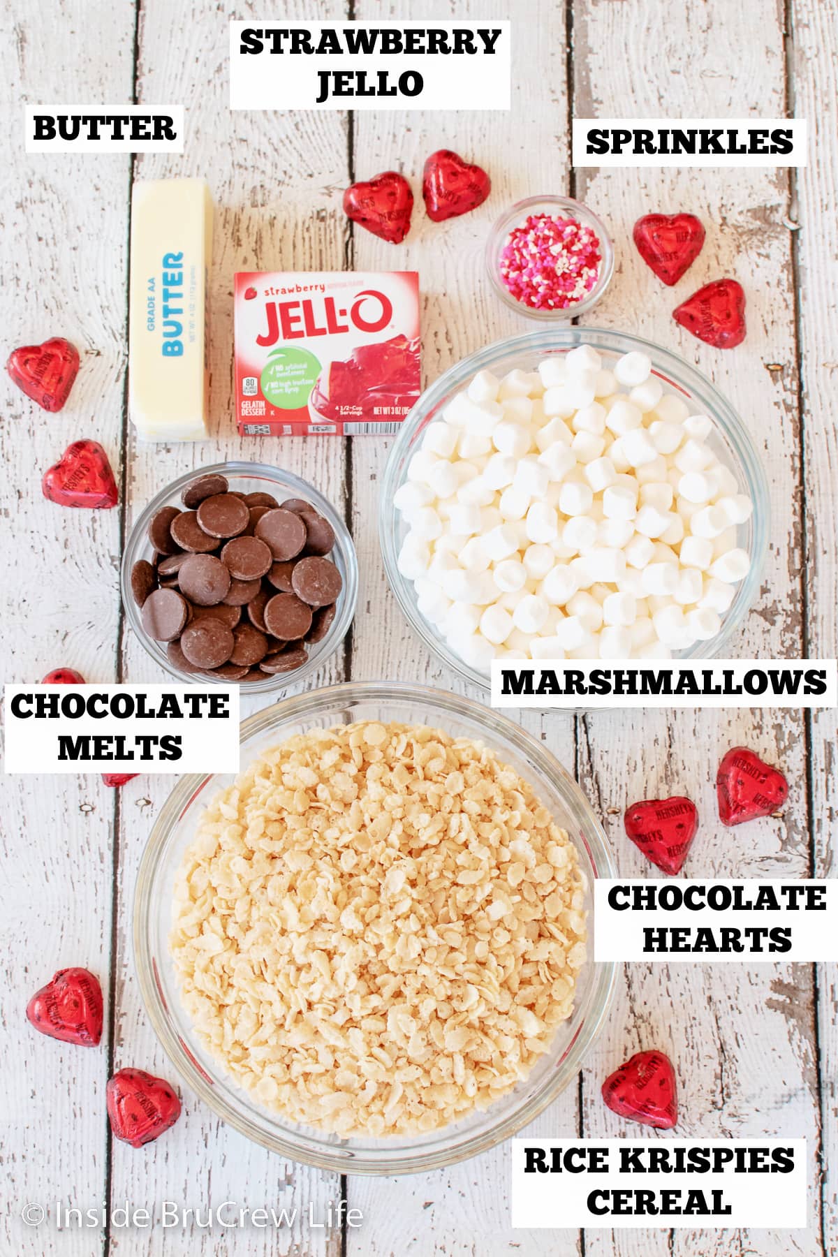 A white board with bowls of ingredients needed to make rice krispie treats with strawberry Jello.