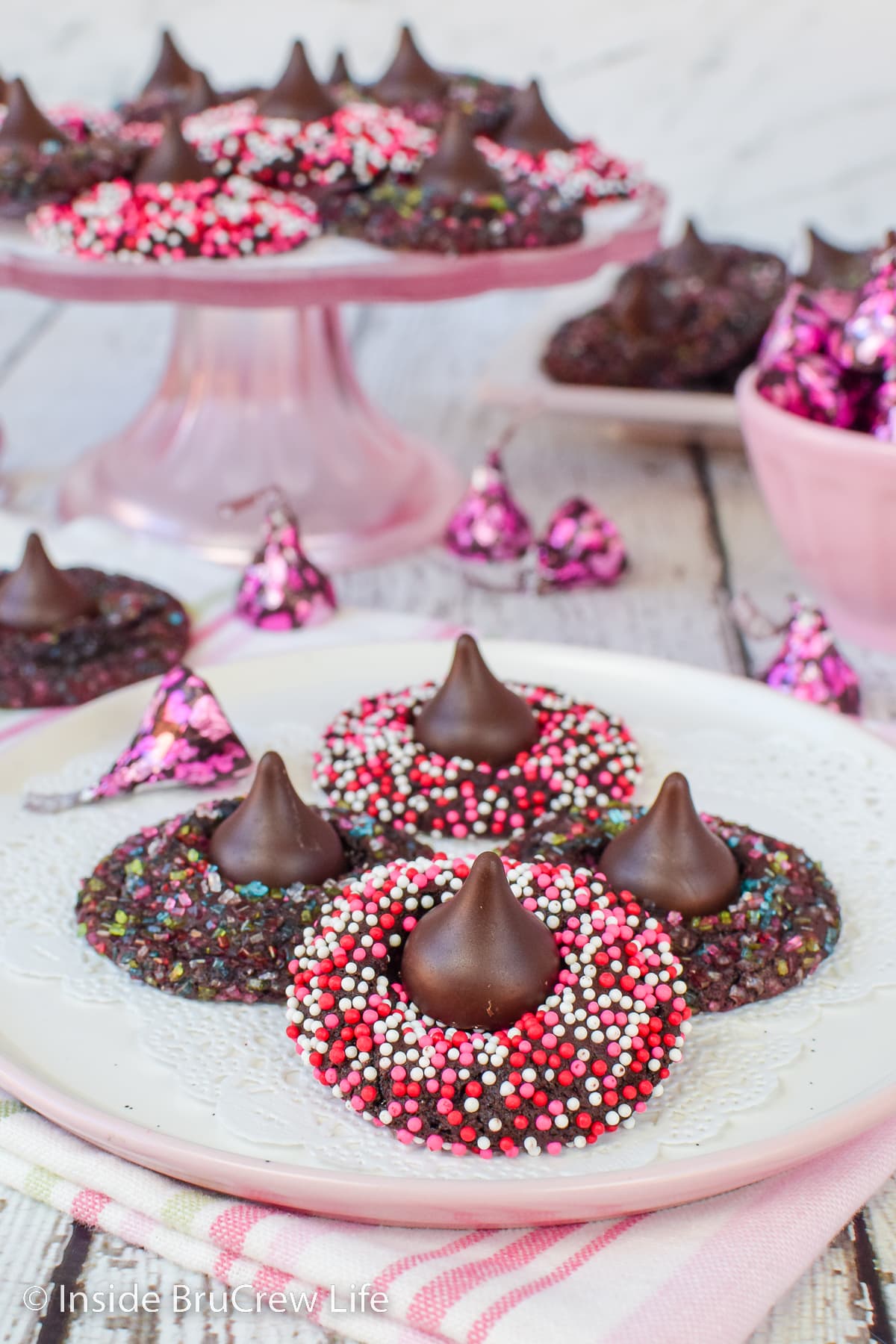 Chocolate sprinkles cookies stacked on a white plate.