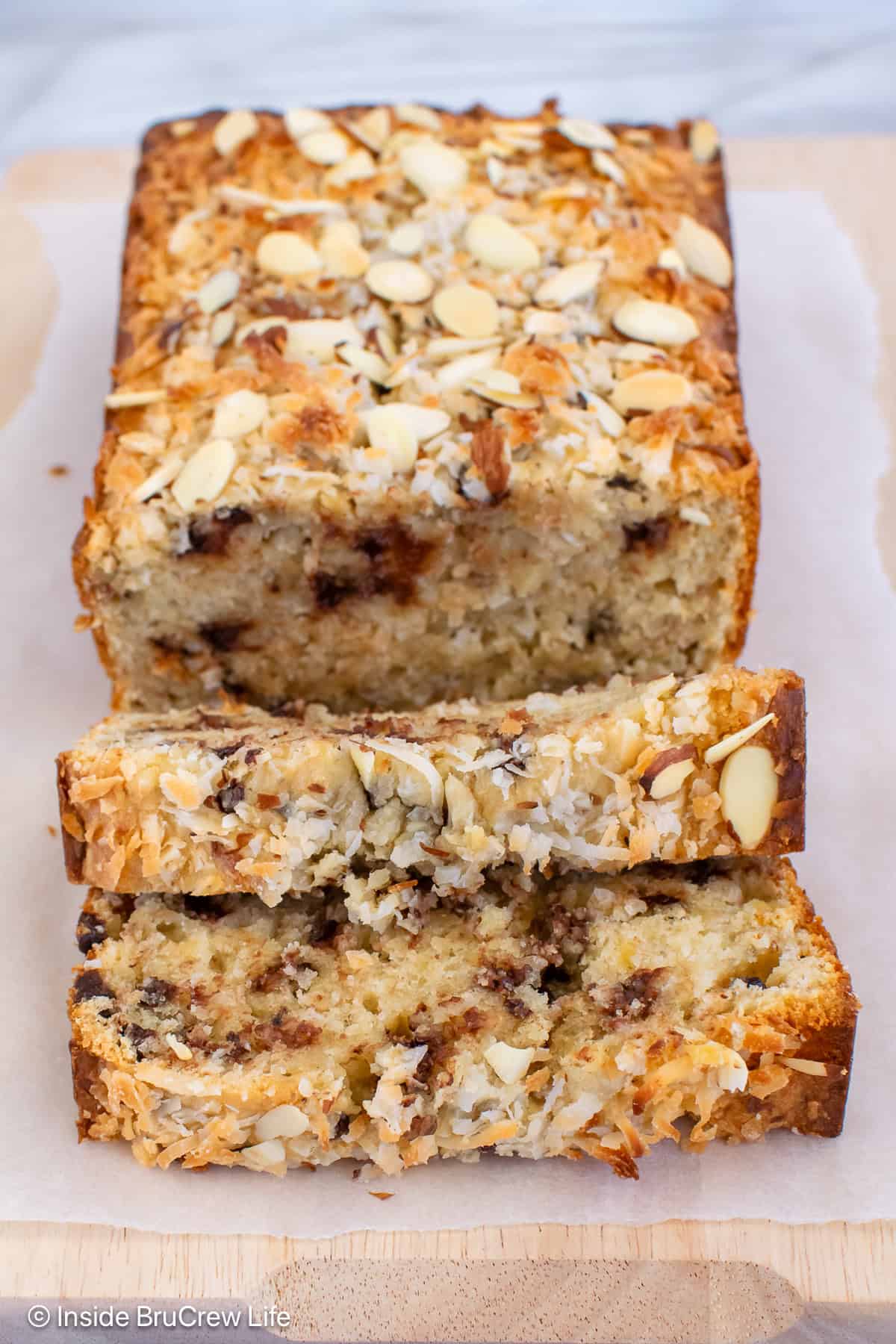 A loaf of almond banana bread on a cutting board with a few slices laying down.