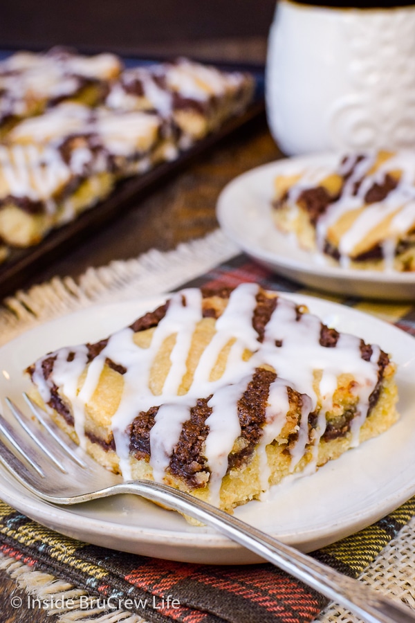 A cream plate with a fork and square of banana nutella snack cake on it