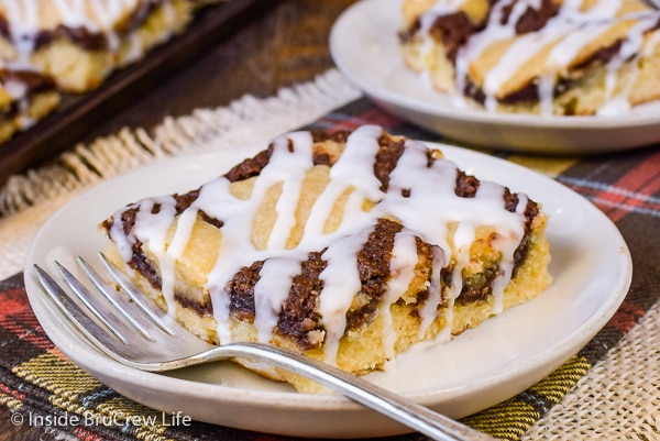 A cream plate with a fork and a square of banana nutella snack cake on it