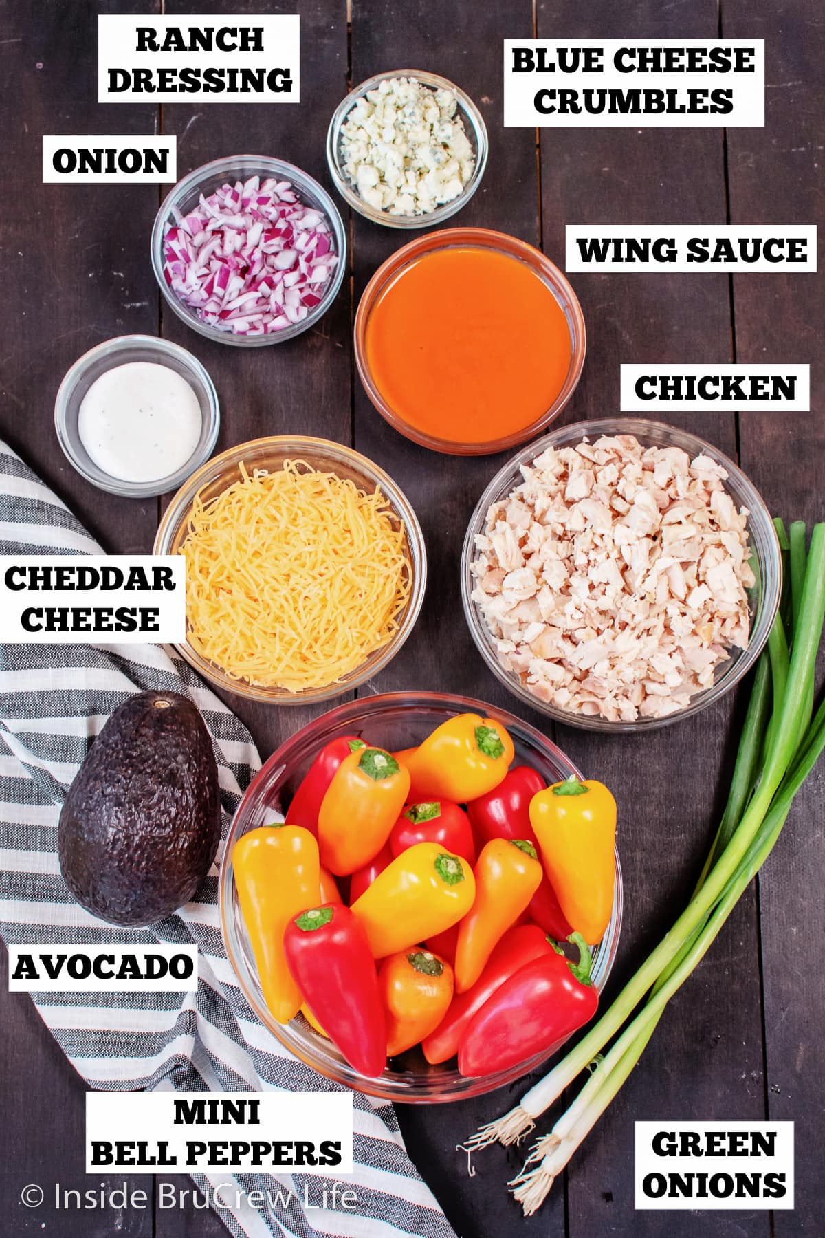 Bowls of ingredients needed to make chicken pepper nachos on a board.