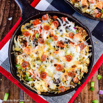 A black skillet filled with cauliflower, cheese, and pizza toppings.