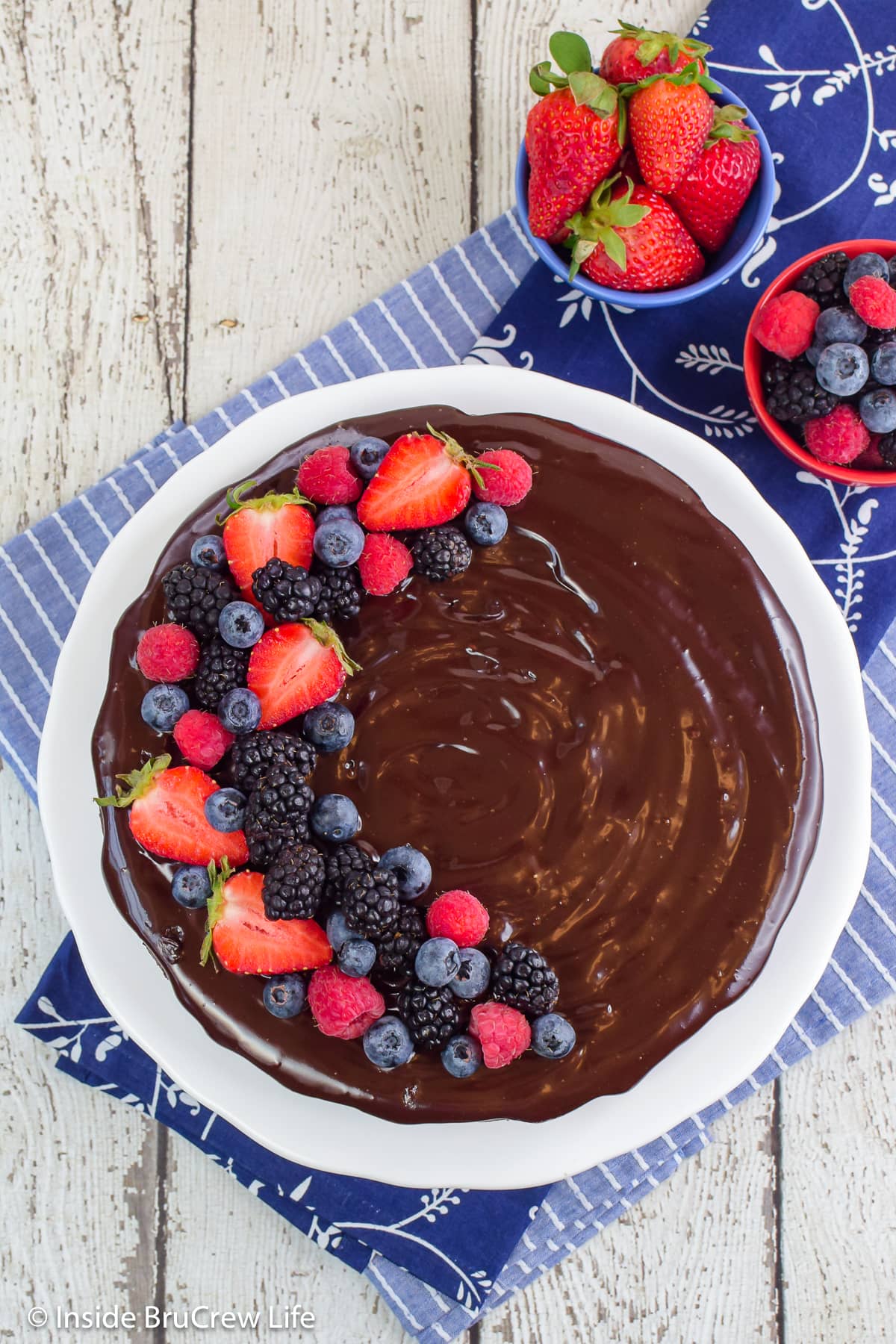 A chocolate cake decorated with fresh berries on a white plate.