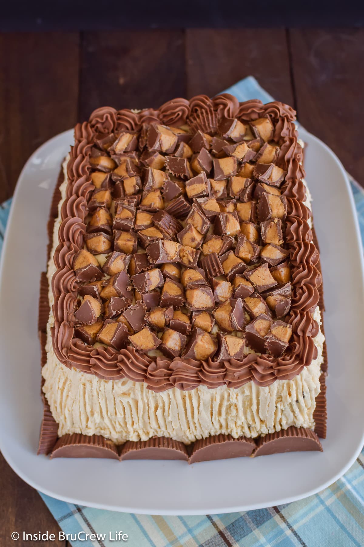 A frosted cake on a plate with chopped peanut butter candies on top.