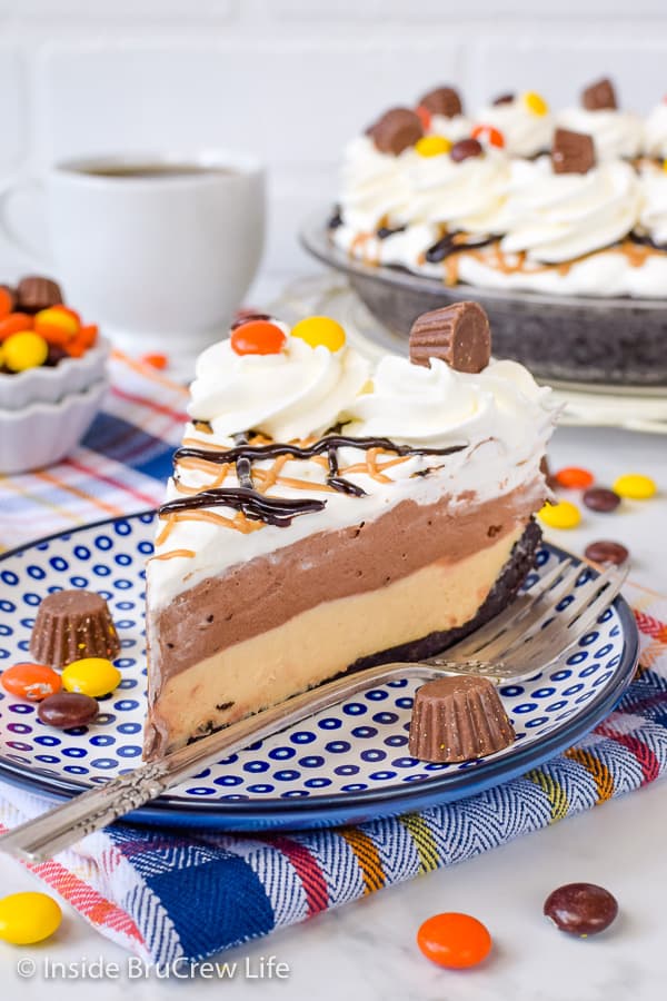 A slice of peanut butter pie topped with chocolate pudding and Cool Whip on a blue and white plate