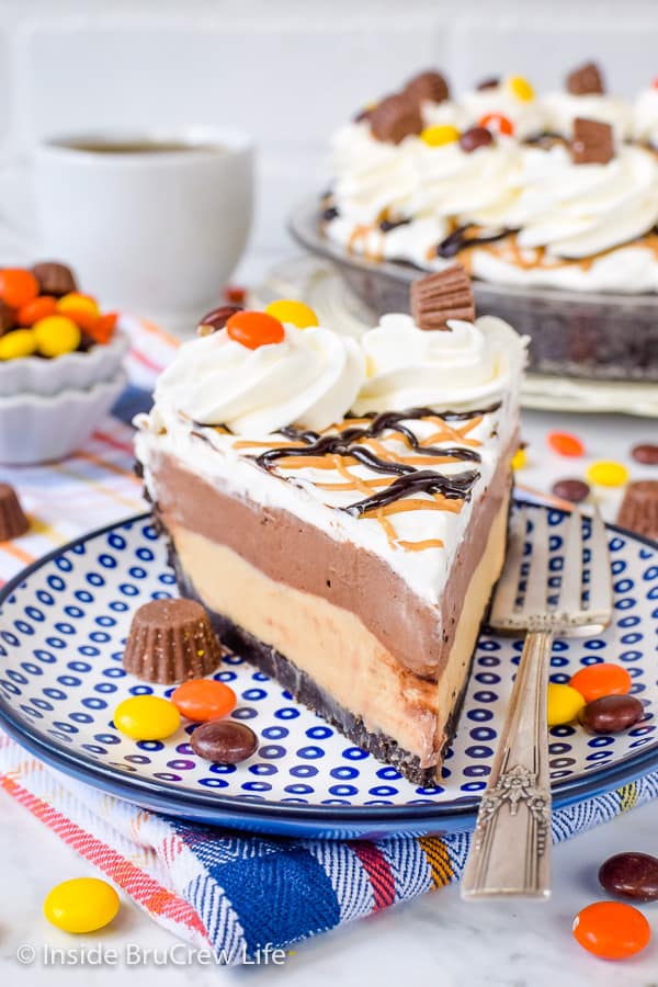 A peanut butter pie slice with layers of chocolate pudding and Cool Whip and Reese's candies