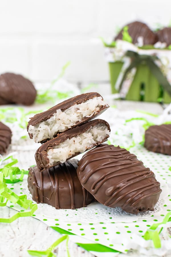 Chocolate covered coconut patties on white parchment paper surrounded by green and white paper pieces.