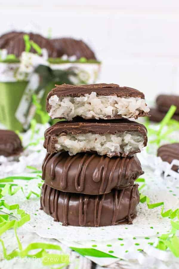 Chocolate covered coconut patties on white parchment paper surrounded by green and white paper pieces.