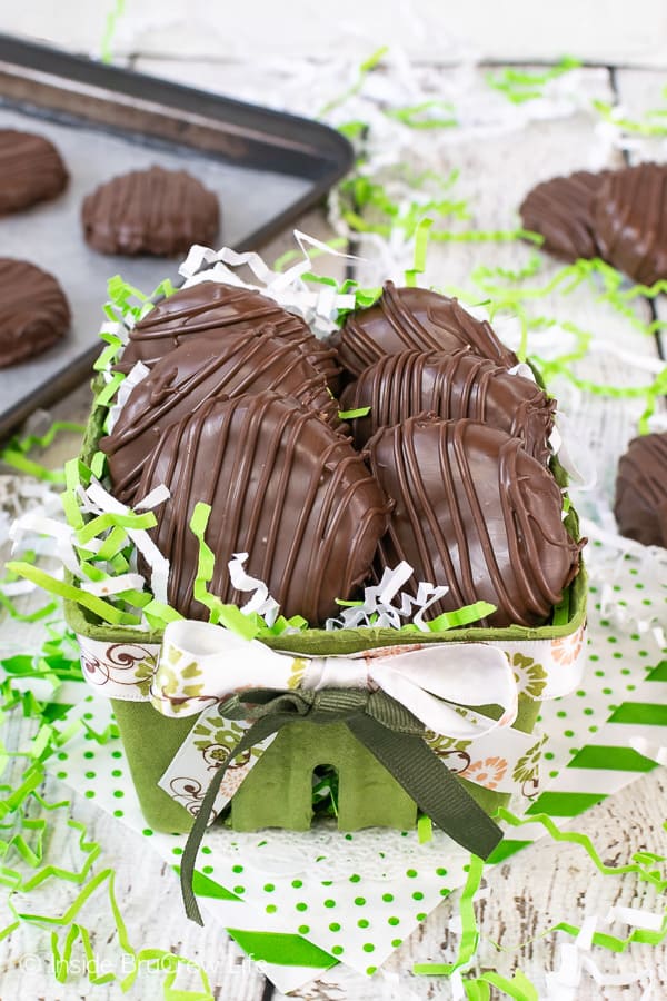 6 chocolate covered coconut patties in a green container with green and white paper ribbons coming out of the container.