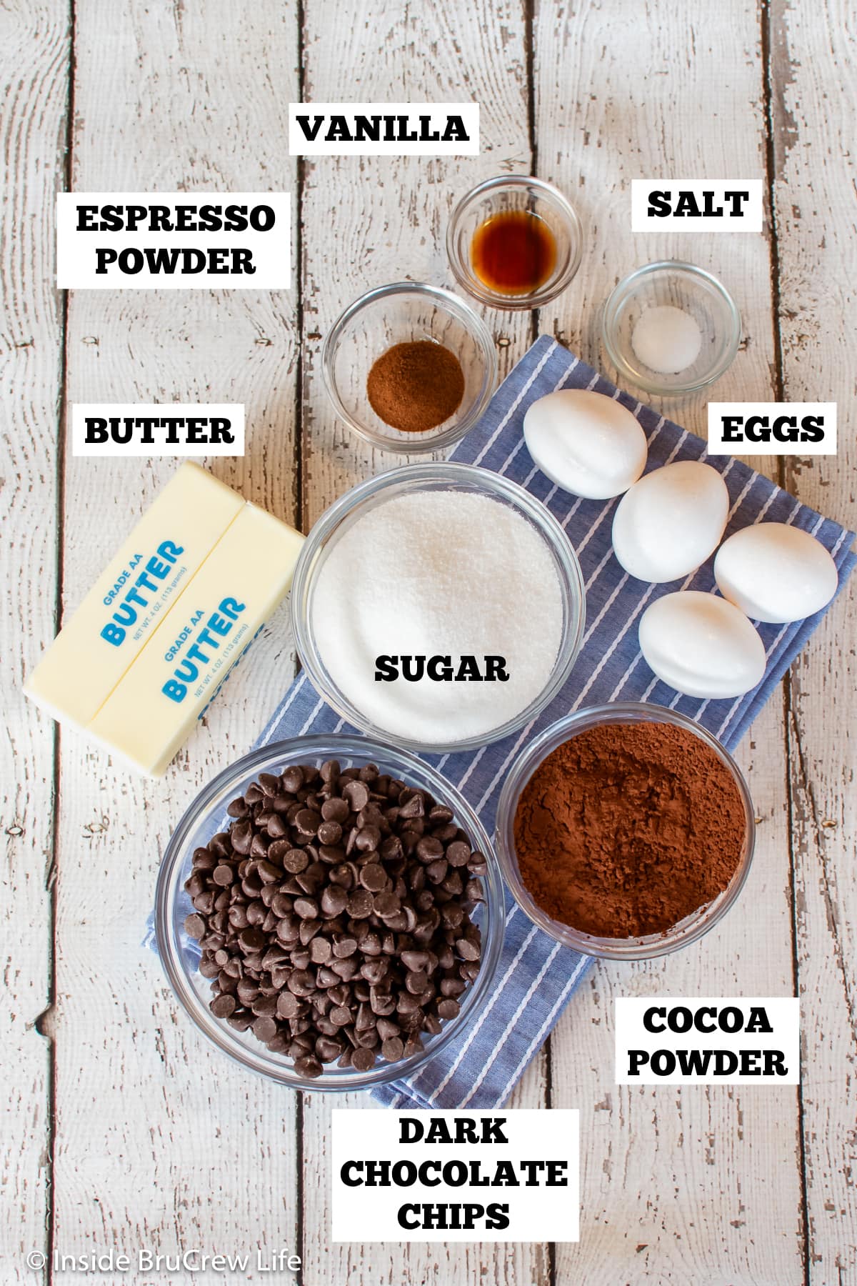 A white board with bowls of ingredients needed to make a chocolate cake without flour.
