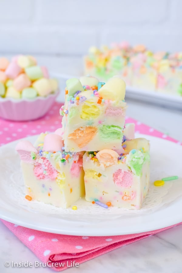 3 pieces of white fudge loaded with colorful marshmallows on a white plate on a pink polka dot napkin.