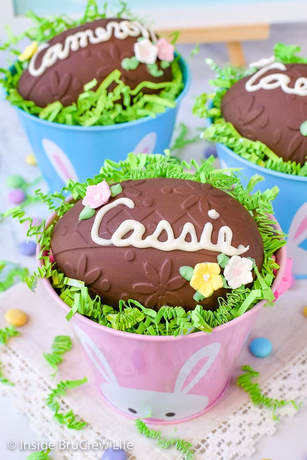 An above angle picture looking into three Easter buckets that have decorated peanut butter eggs in the top.