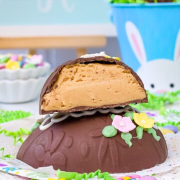 A chocolate peanut butter egg on an Easter napkin with another half of a Reese's egg stacked on top of it