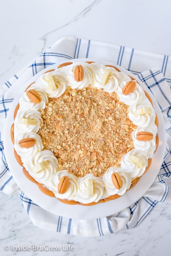 Overhead picture of a banana cheesecake topped with banana pudding, whipped cream, and crushed vanilla wafers.