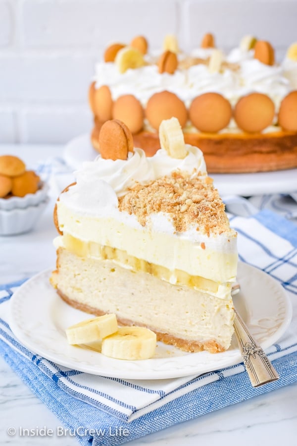 A white plate with a slice of Banana Pudding Cheesecake on it and the rest behind it.