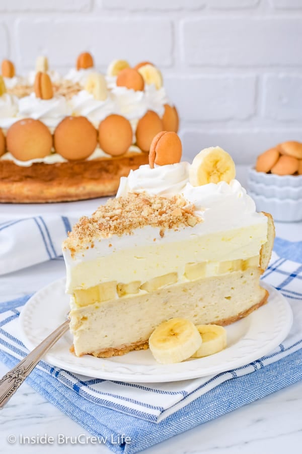 A white plate with a slice of banana pudding cheesecake and a fork on it.