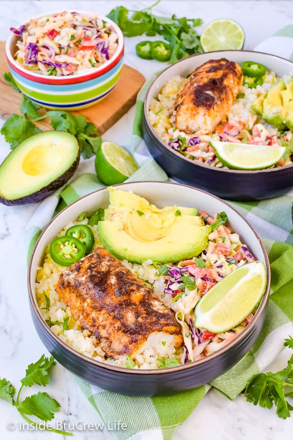 Two fish taco bowls filled with baked cod, cauliflower rice, and homemade coleslaw.