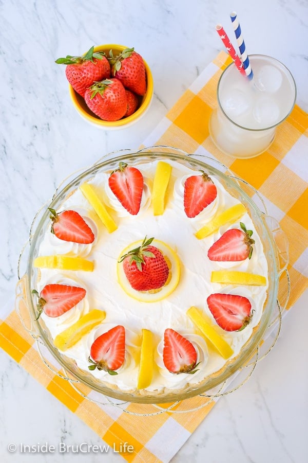 Overhead picture of the top of a lemon cream strawberry pie on a yellow and white towel.