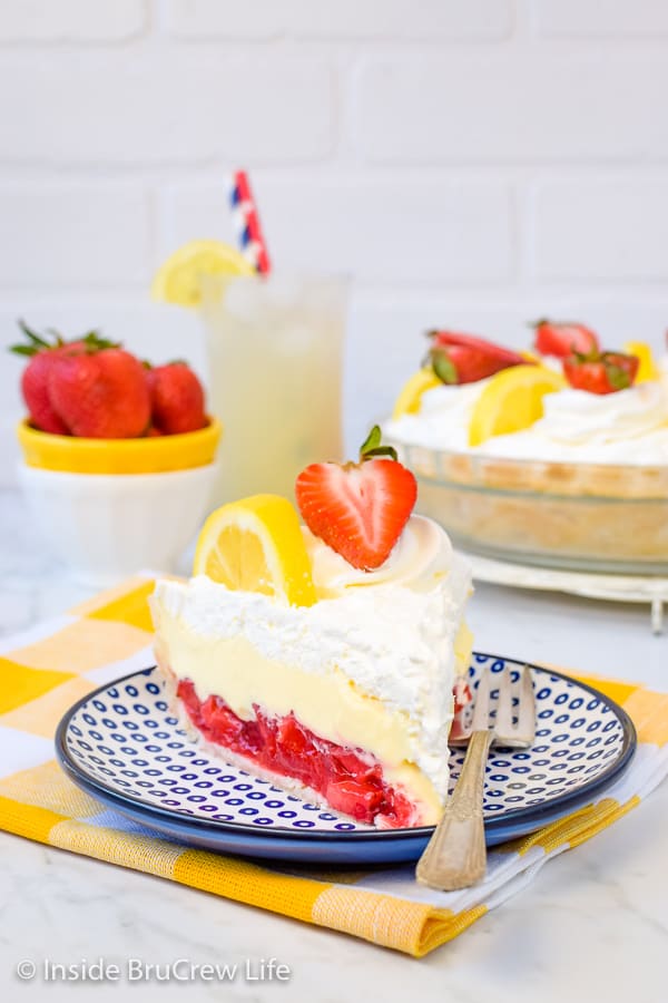 A slice of lemon cream strawberry pie on a white and blue plate.