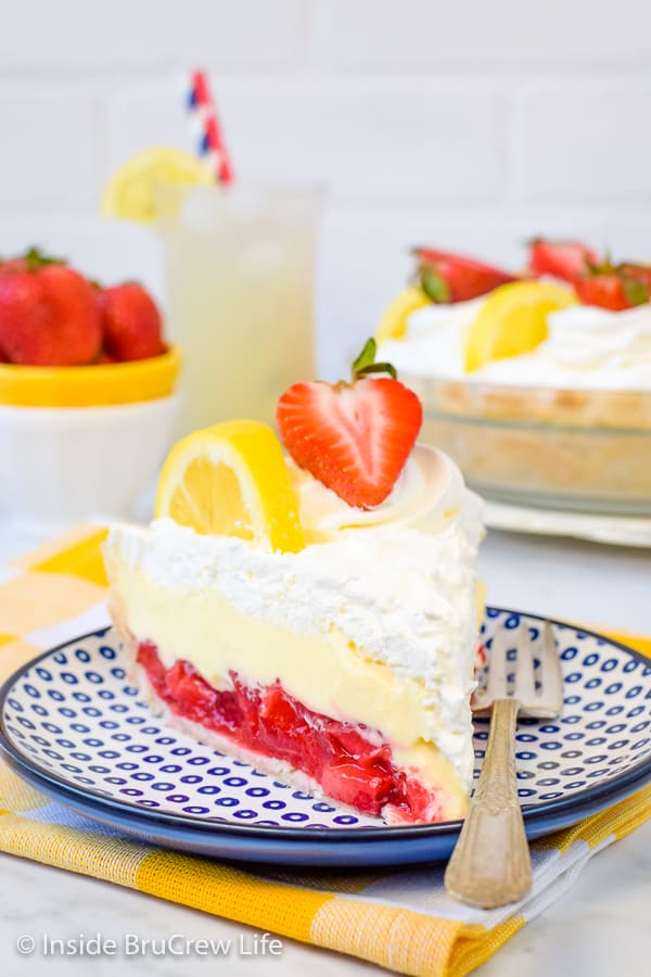 A white and blue plate with a slice of lemon cream strawberry pie on it.