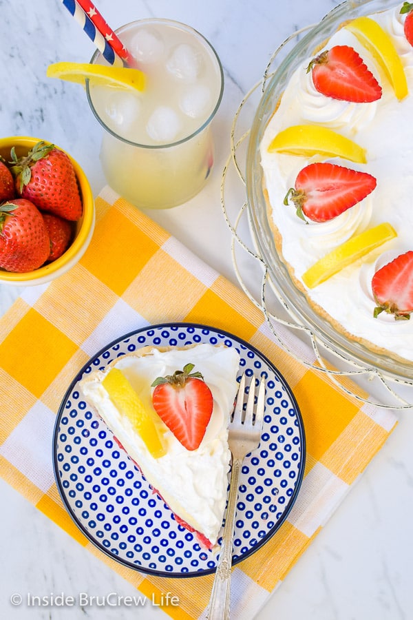 Overhead picture of a blue and white plate with a piece of lemon cream strawberry pie on it and pie plate.