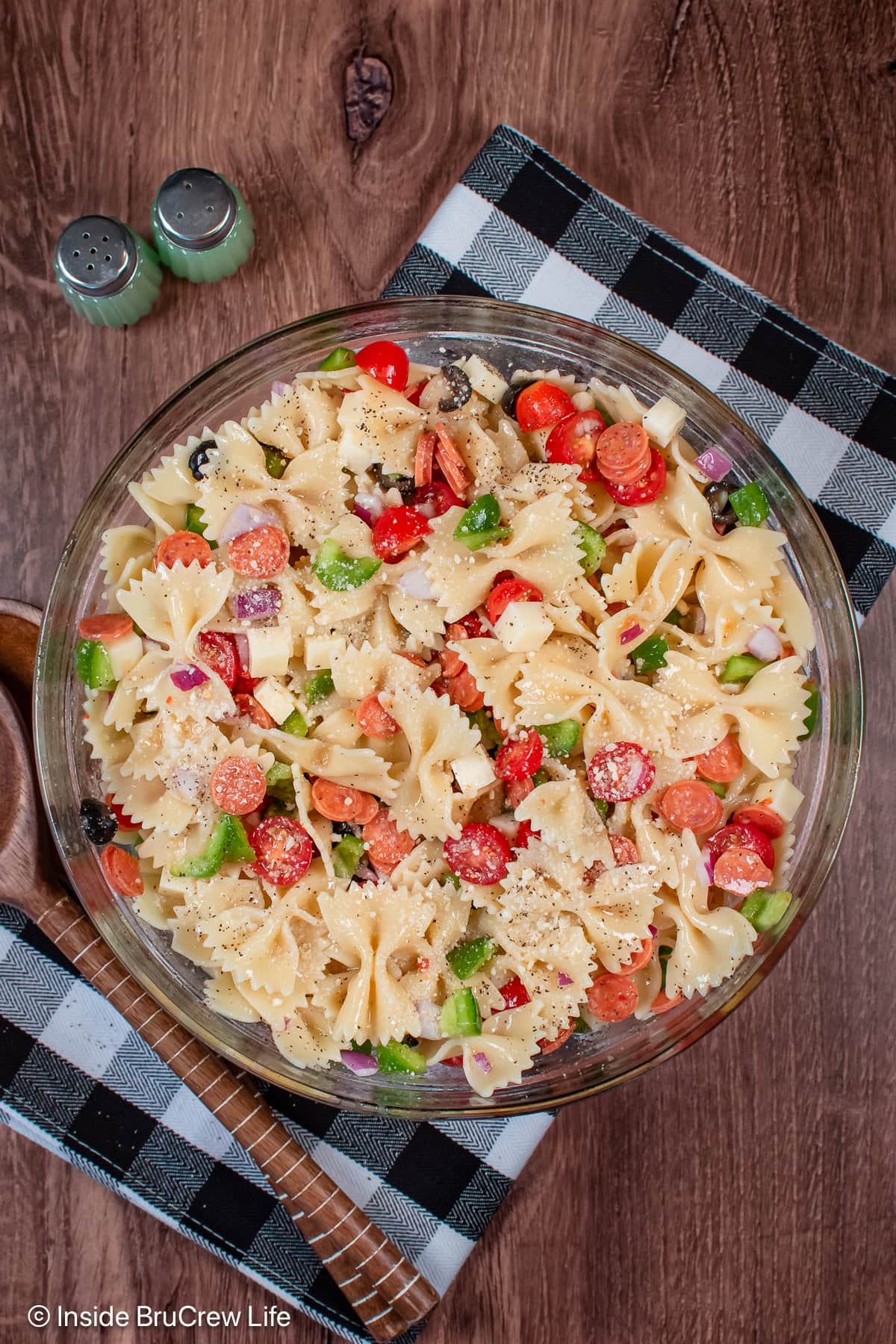 A bowl of cooked pasta and pizza toppings.