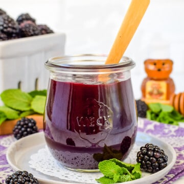 A clear jar filled with blackberry preserves.