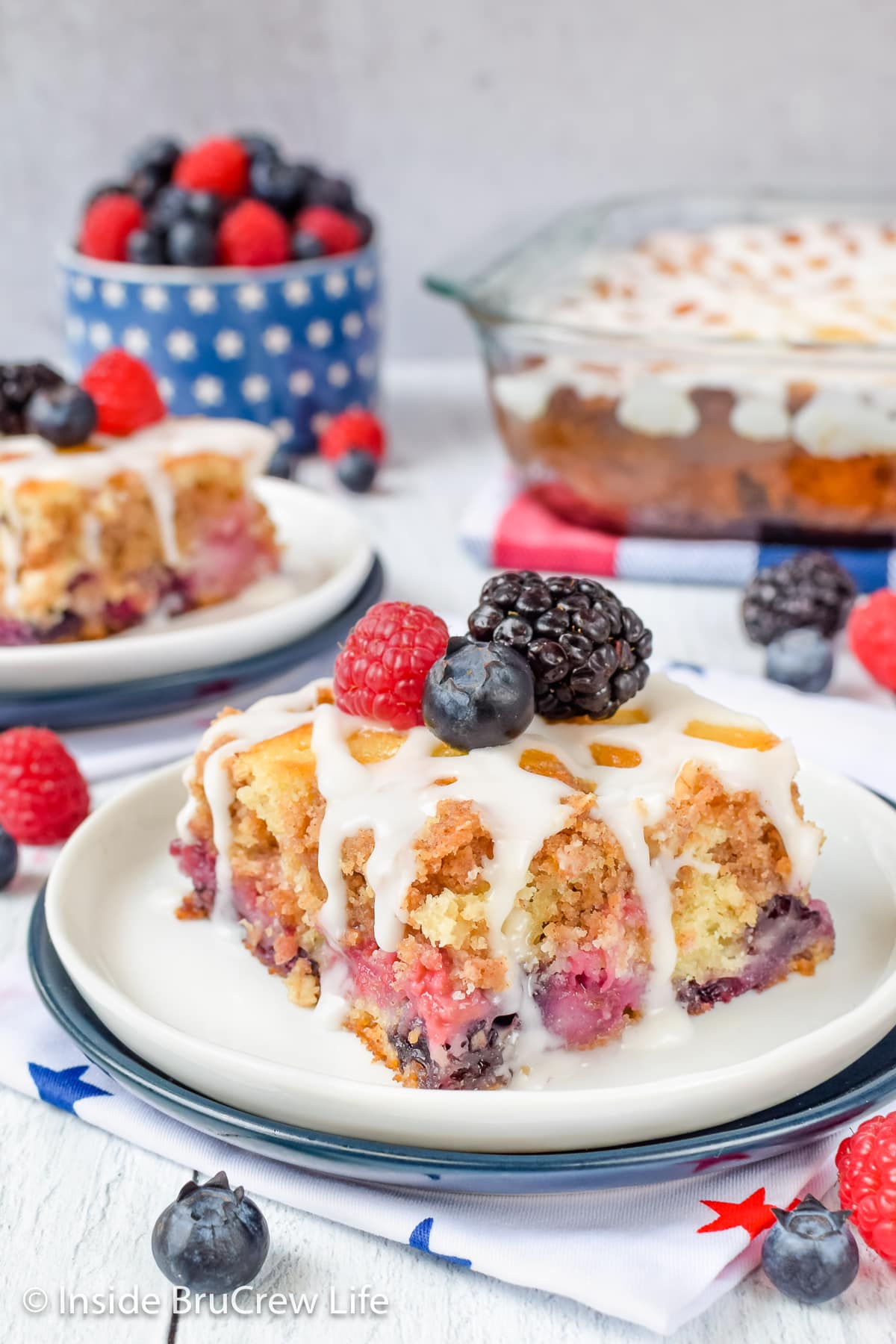 A slice of mixed berry cake on a plate with berries on top.