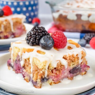 A slice of mixed berry cake on a plate with berries on top.