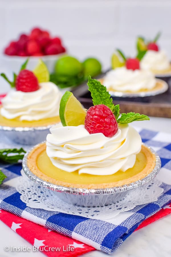 Two mini key lime pies on a blue and white towel.