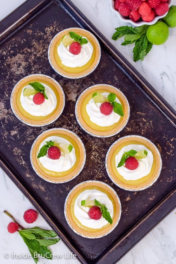 Overhead picture of 6 mini key lime pies on a metal sheet pan.