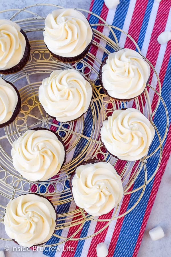 Overhead picture of a white wire tray with cupcakes topped with swirls of marshmallow frosting on it.
