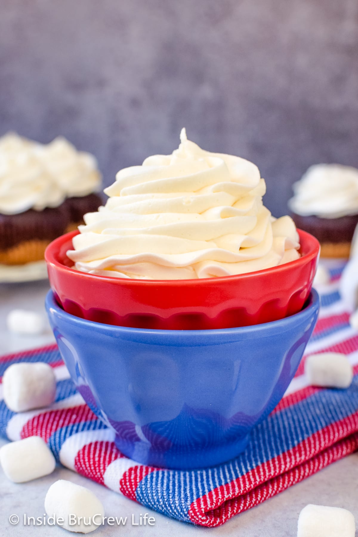 A red and blue bowl filled with a swirl of buttercream icing.