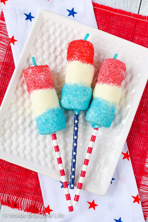 A white plate with three red white and blue firecracker marshmallow pops on it.