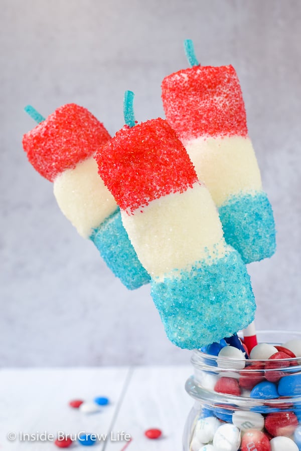 Close up of red white and blue marshmallow pops stuck in a jar of candies.