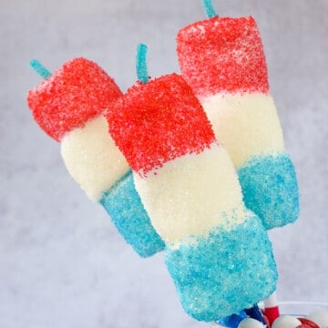 Three red white and blue marshmallow pops on straws.